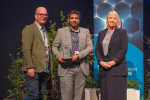 Two men from Northpower with their EEA award, standing next to EEA President Josie Boyd